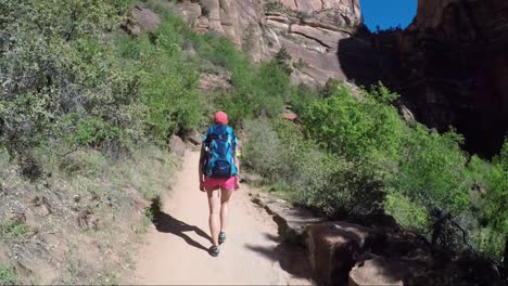 young woman wearing backpack is walking to angel's landing in zion national park in utah, usa