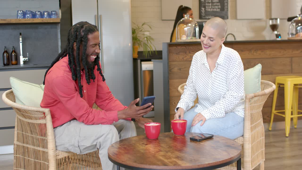 Diverse friends laughing and sharing phone screen at cafe after barista opening fridge