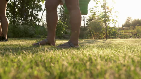 girl and woman in black sneakers and sleepers standing on meadow in a garden holding a bucket