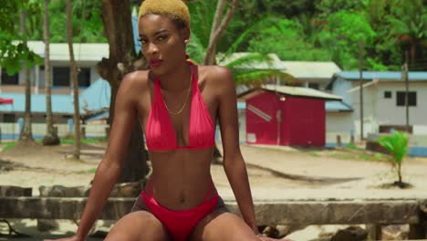 A-young-woman-with-dark-skin-enjoys-a-tropical-day-on-a-Caribbean-beach,-dressed-in-a-red-bikini