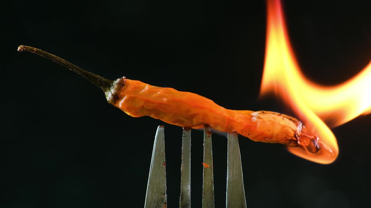 A fork with a fresh chili pepper on it is flamb&eacute;ed