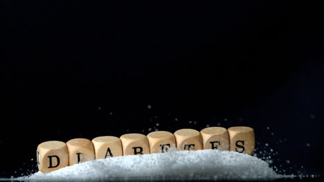 dice spelling diabetes falling over a pile of sugar on black background