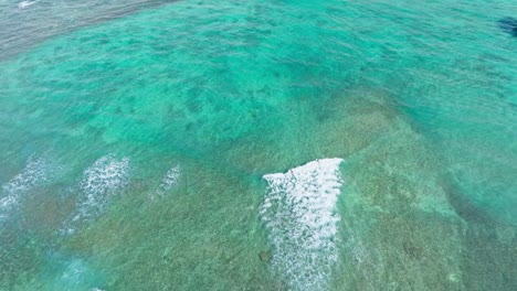 Drohnenaufnahmen-Eines-Surfers-Auf-Einer-Großen-Welle-Im-Türkisblauen-Ozean,-Eines-Surfers-Im-Pazifik,-Der-Auf-Kreuz-Und-Quer-Verlaufenden-Wellen-Auf-Das-Ufer-Zusteuert