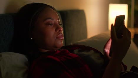 woman using phone in bed at night