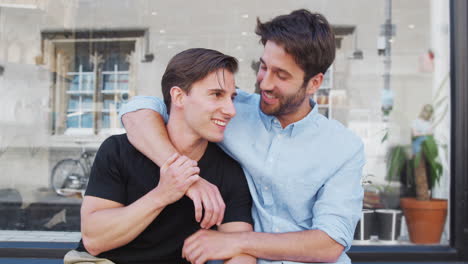 loving male gay couple hugging outside coffee shop