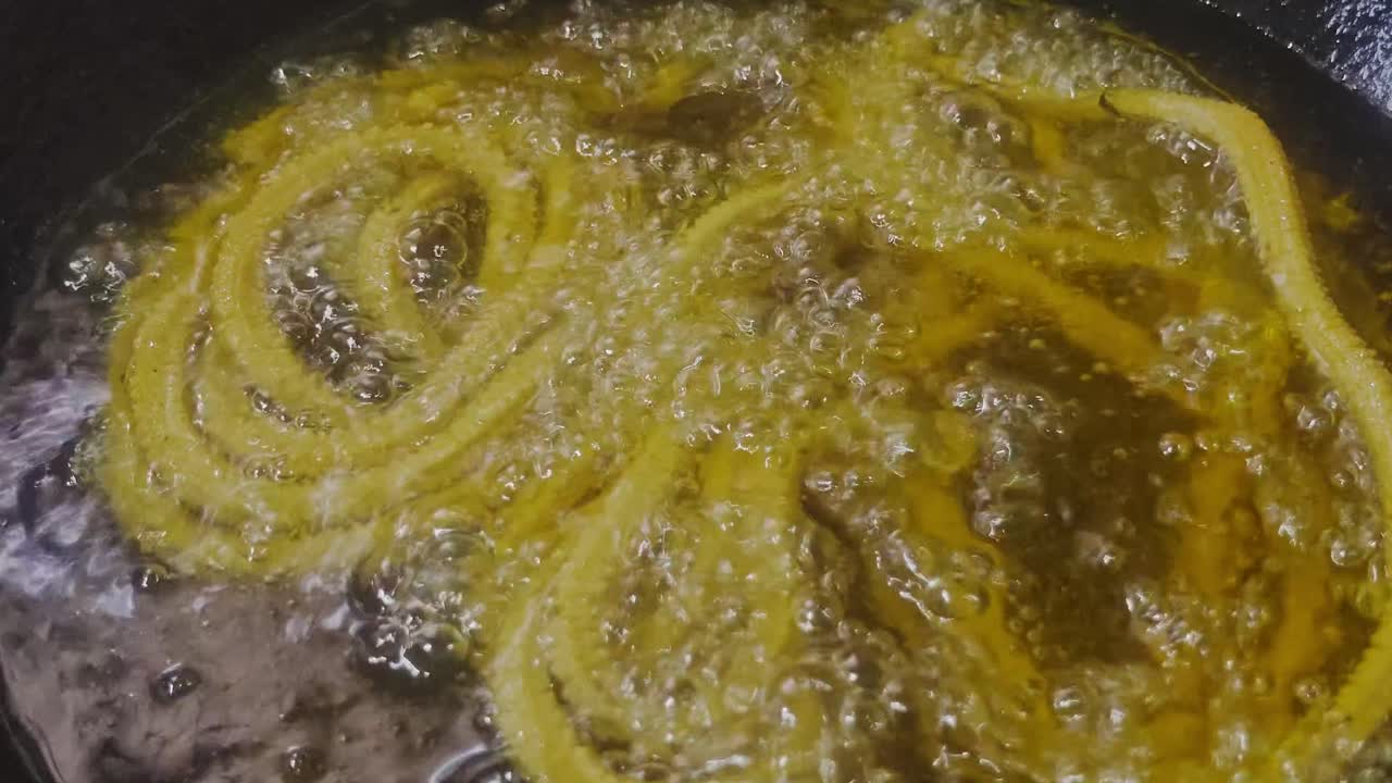 Close-up view of traditional Indian murukku snack being deep-fried in bubbling hot oil. internal shot, stable shot, 4k