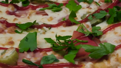 close-up of a delicious pizza with ham, tomatoes, pickles, and parsley