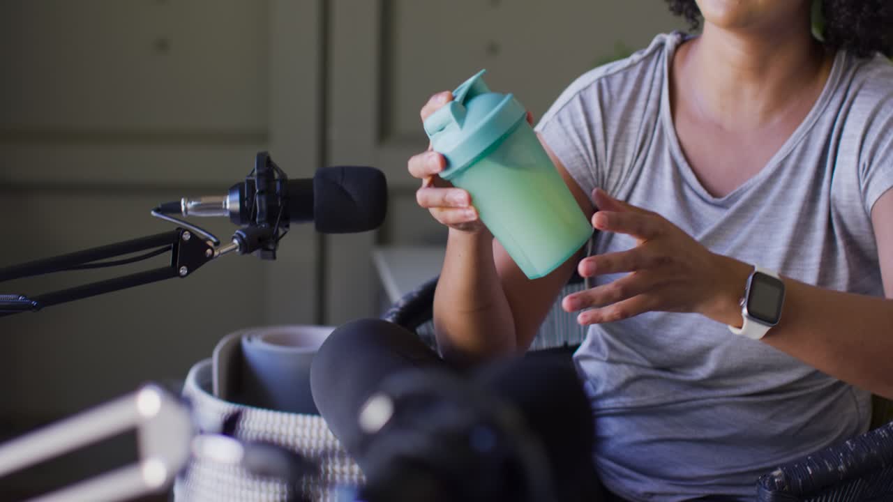 La telecamera si sposta sui conduttori afroamericani, una donna prende uno shaker verde menta e mostra il coperchio al microfono.