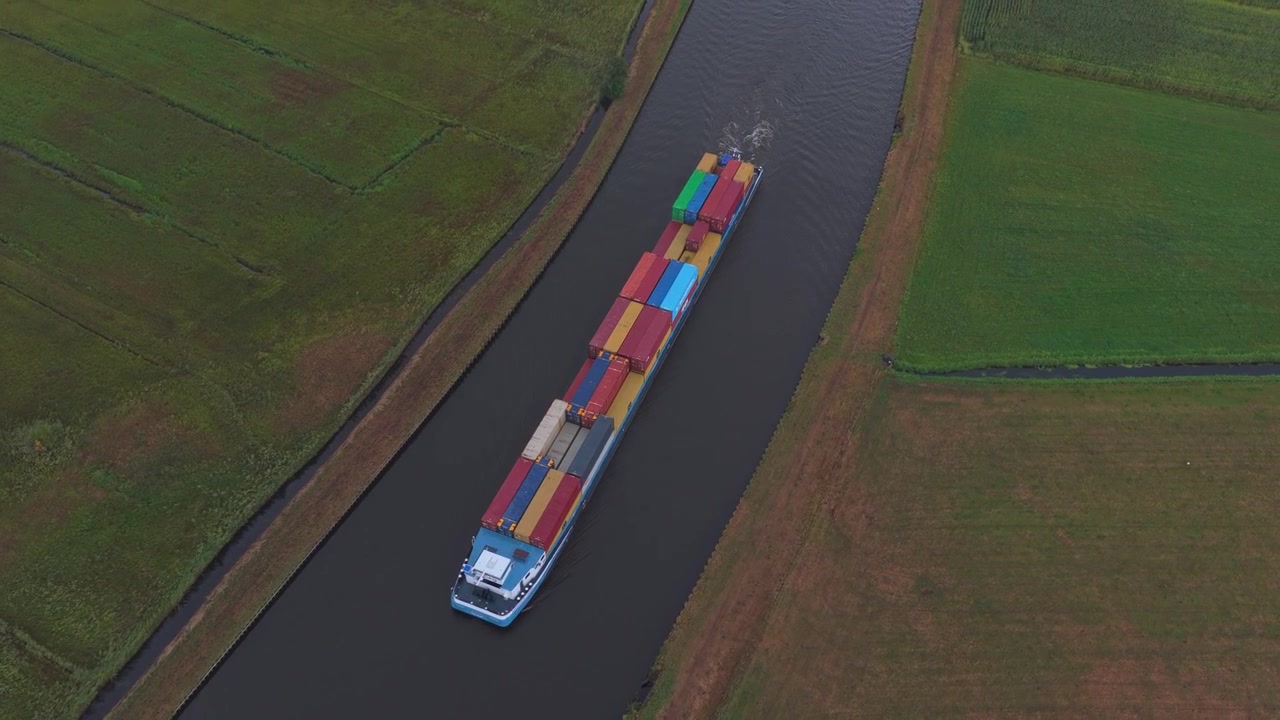 Luftfoto af lastpram, der transporterer containere langs en kanal