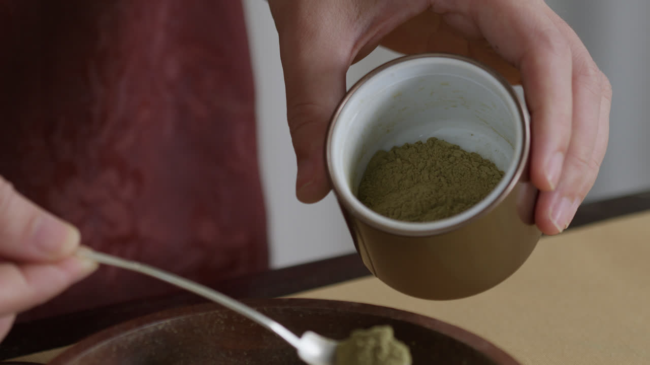 colocando té molido sobre una taza preparando la tradicional ceremonia del té chino