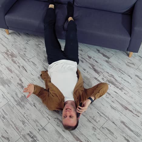 man relaxing using mobile phone. happy young man talking on mobile phone and lying on the floor
