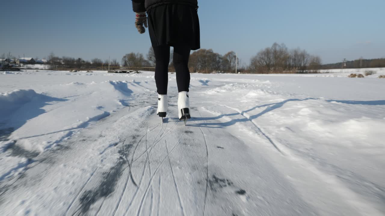 색 피겨 스케이트를 입은 여성이 겨울에 얼어붙은 연못에서 스케이팅을 하고 있습니다.