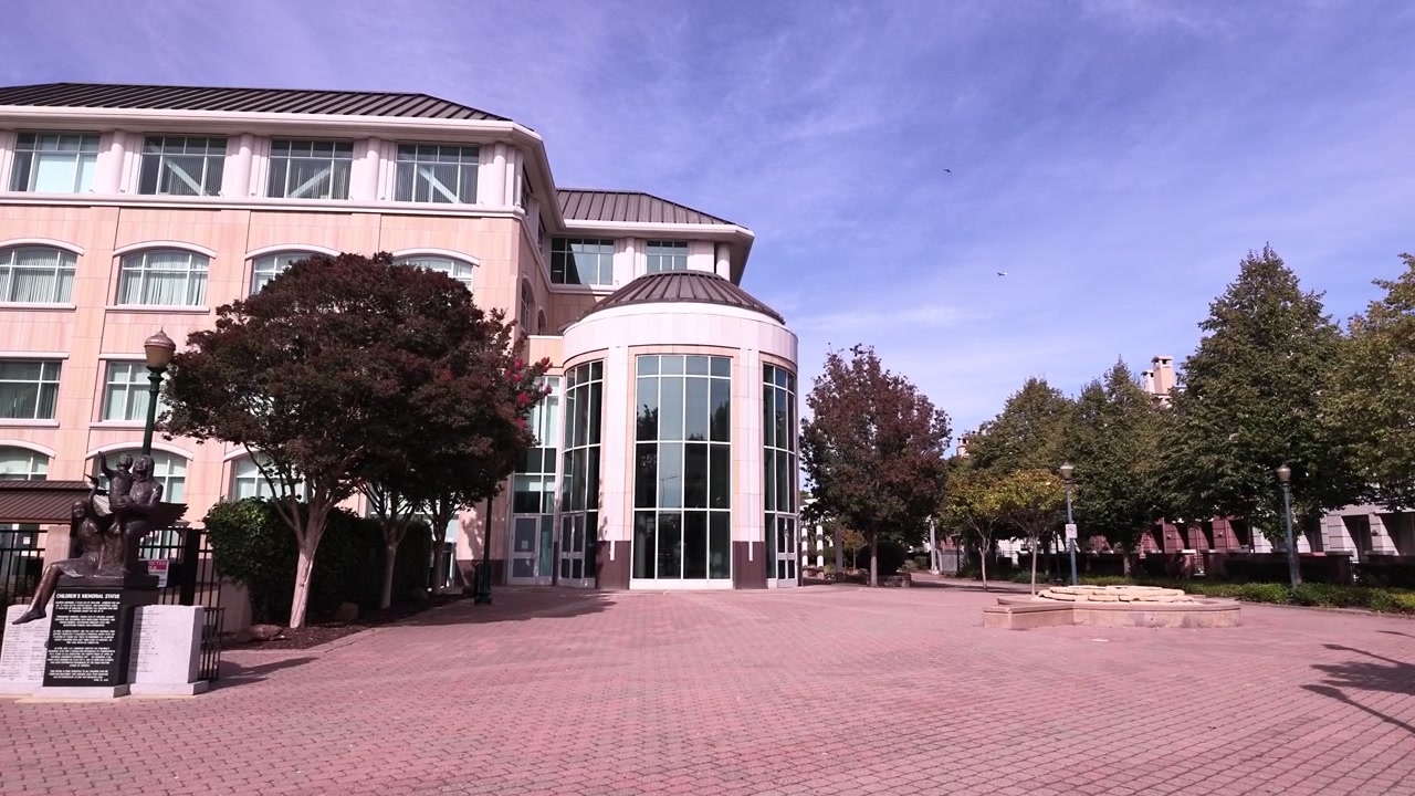 Moderna facciata architettonica dell'edificio del Municipio di Hayward, con una piazza pubblica e alberi circostanti in una giornata di sole nella Bay Area di San Francisco, che rappresenta il governo locale e la vita urbana