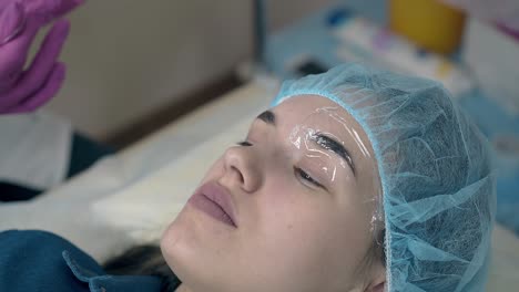 young lady goes through brows tattooing procedure in clinic