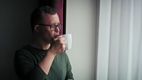 Nachdenklicher-Kaukasischer-Mann-Mit-Down-Syndrom,-Der-Im-Wohnzimmer-Kaffee-Trinkt.