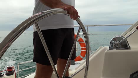 parte media de un capitán dirigiendo un velero en un día nublado
