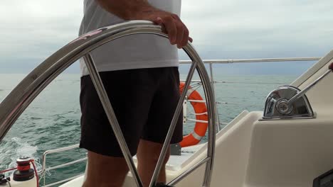 midsection of a captain steering a sailing boat on an overcast day