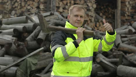 man lumberjack woodcutter with big axe. sawn logs, firewood background. thumb up