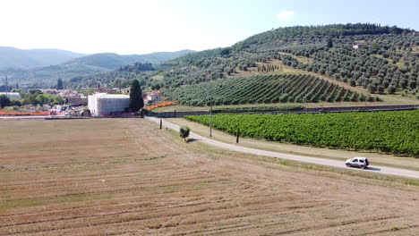 conducción de automóviles junto a viñedos verdes, toscana, italia