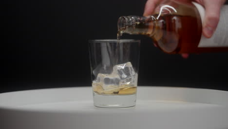 whisky die over ijsblokjes in een whiskyglas wordt gegoten