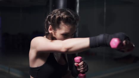 Mujer-Joven-Entrenando-Con-Las-Manos-Envueltas-En-Cintas-De-Boxeo-Sosteniendo-Pesas.-Tiro-En-Cámara-Lenta