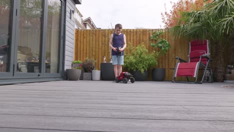 young boy at home outdoors in the garden playing with his rc car, truck, 4 x 4