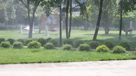 sprinkler system watering a green lawn in a park.