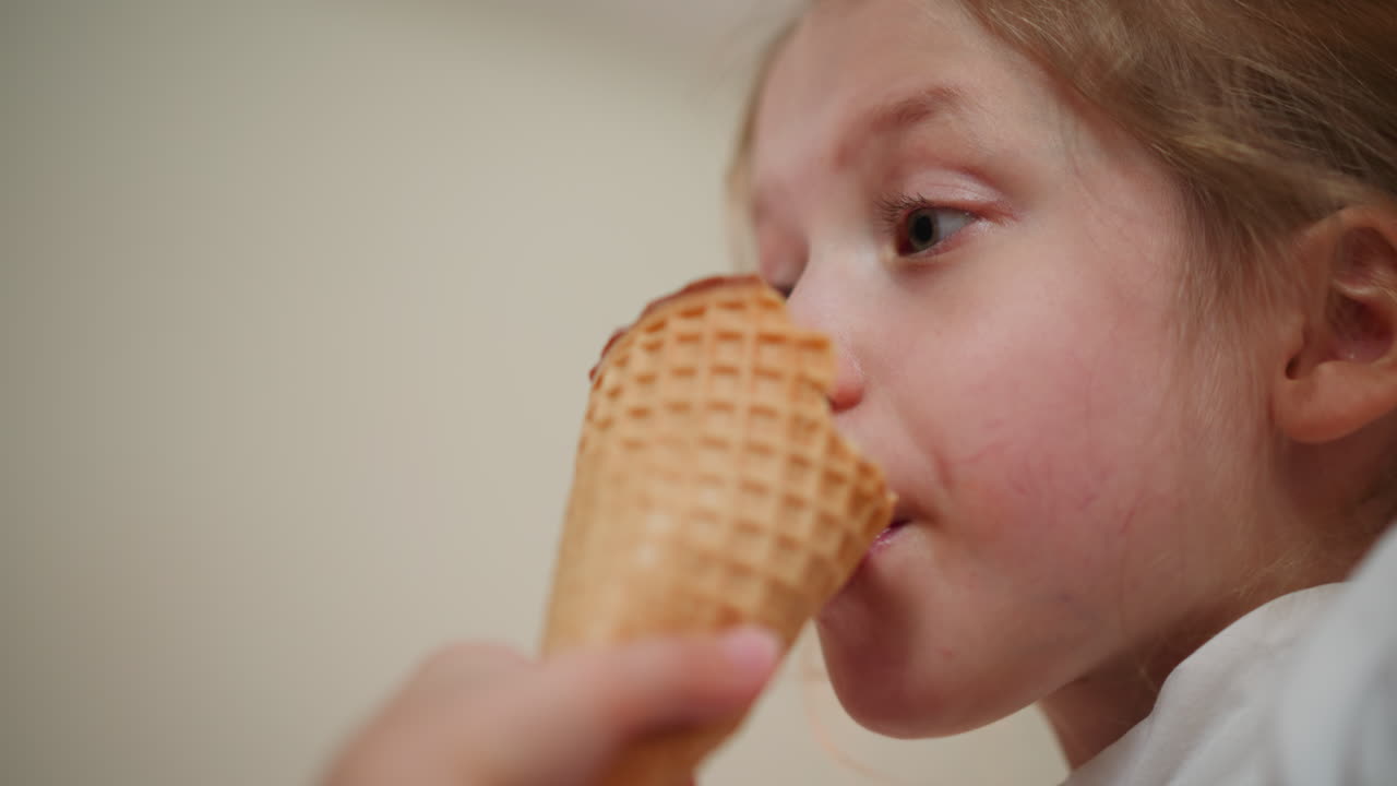 Close up of young girl enjoying ice cream cone, savoring sweet treat with soft expression, natural lighting enhances innocence and joy of moment, showcasing carefree childhood