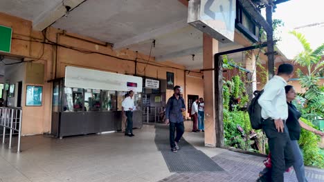 people enter the kandy train station platform, showcasing daily commuting in sri lanka. the scene captures travelers amidst lush greenery and a bustling atmosphere typical of public transportation.