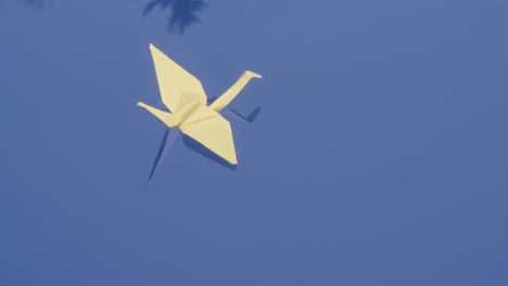 closeup of pastel color origami swan floating on water surface