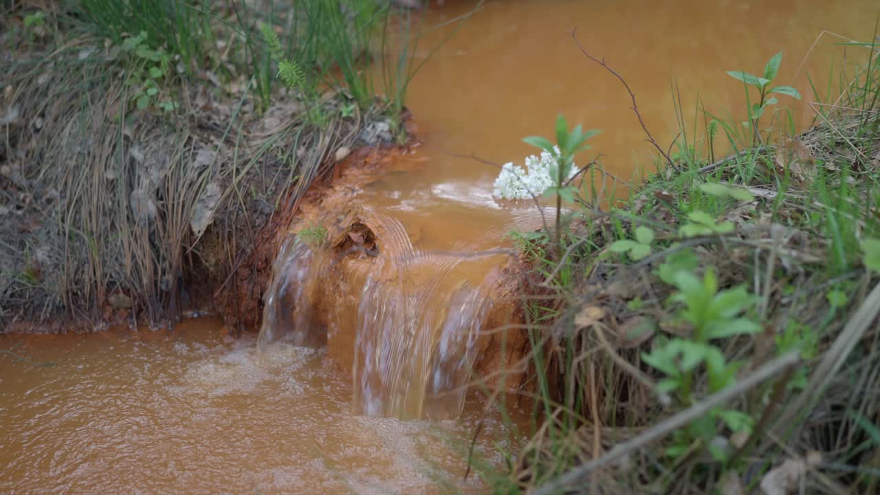 un arroyo fangoso con una cascada de agua corriente en un soleado día de primavera