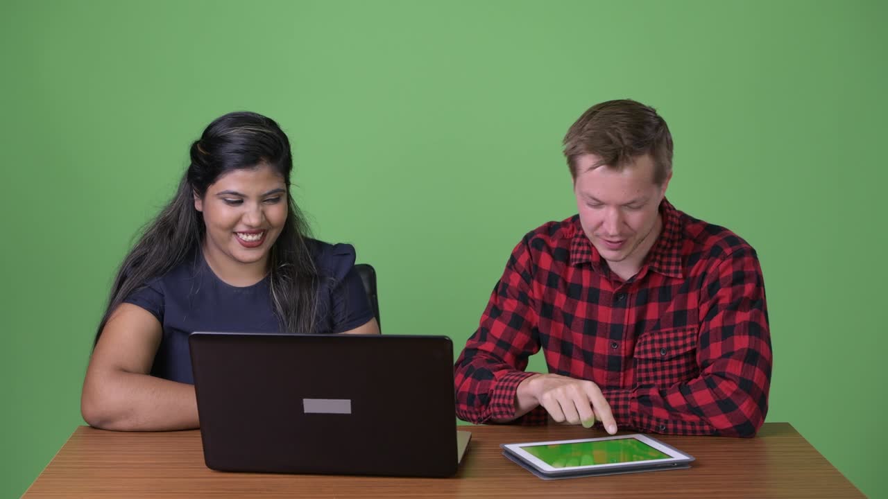 joven pareja de negocios multiétnica juntos contra un fondo verde