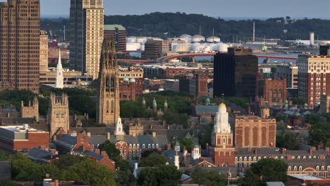 aerial zoom of historic cathedral and harkness tower in new haven, connecticut. wide shot. old university and downtown buildings in center. sunset time