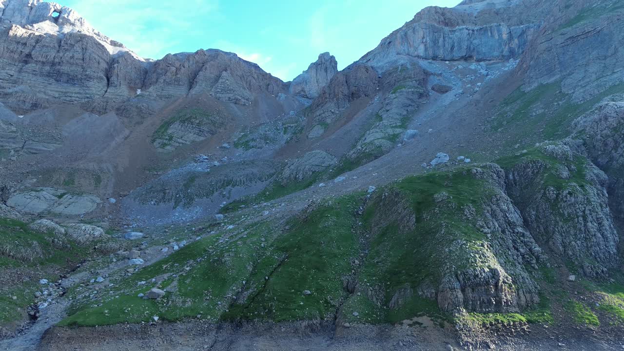 Majestic aerial footage of the rugged Valle de Ip landscape near Canfranc, Aragón. Soaring over dramatic mountain terrain under clear blue skies, evoking a serene wilderness