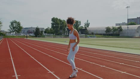 mujer estirándose en una pista de atletismo