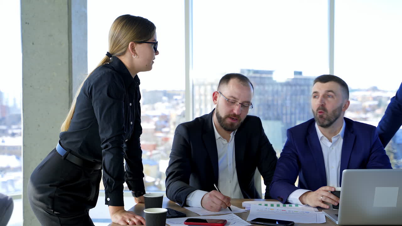 Cheerful business partners communicate. Group of successful entrepreneurs talking in office on the background of windows. Business colleagues work together.