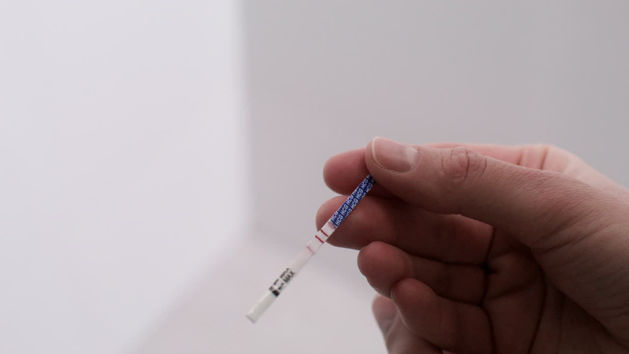 Hand holding pregnancy test on bathroom