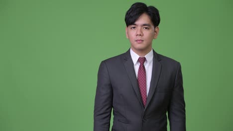 joven y guapo hombre de negocios asiático mostrando algo