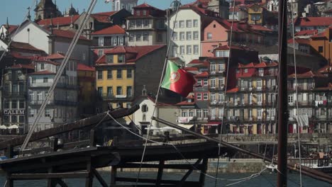 medium shot, portugal flag hanging on a boat line waving, scenic view of the old town porto in the background