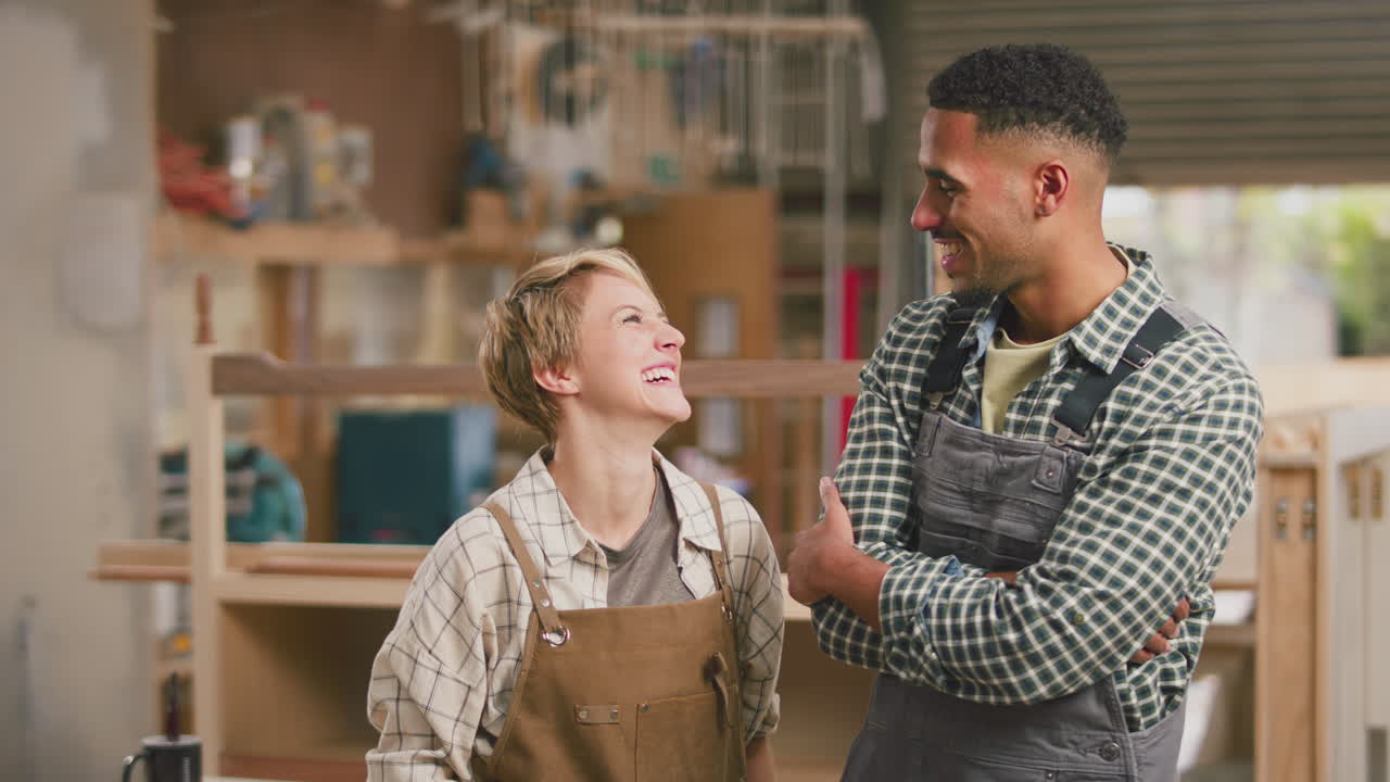 Ritratto di apprendisti falegnami sorridenti (uomo e donna) al lavoro in una falegnameria