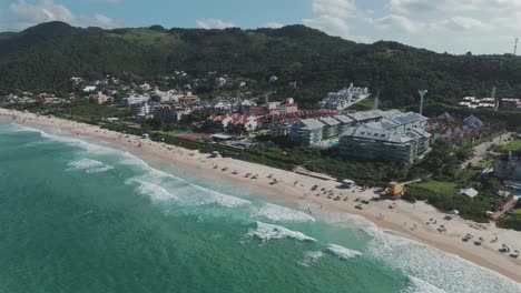 a drone advances over praia brava in florianopolis, capturing its stunningly clear waters and luxurious condominiums