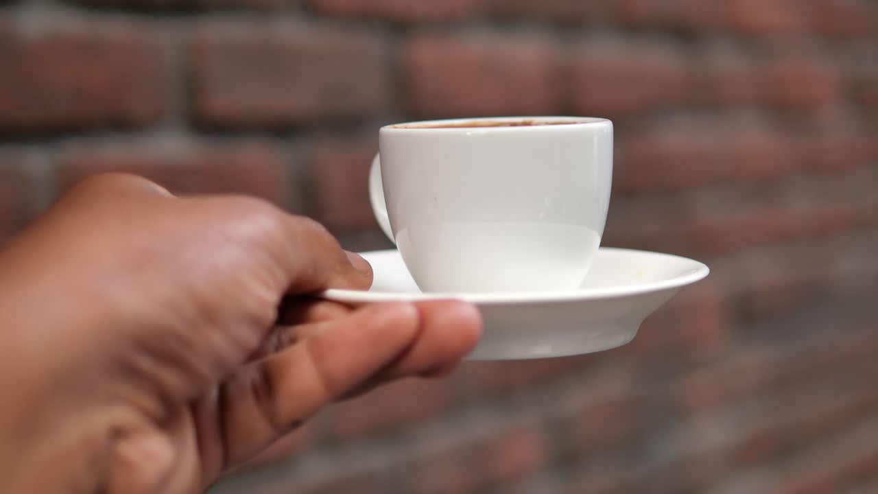 mano sosteniendo una pequeña taza de café