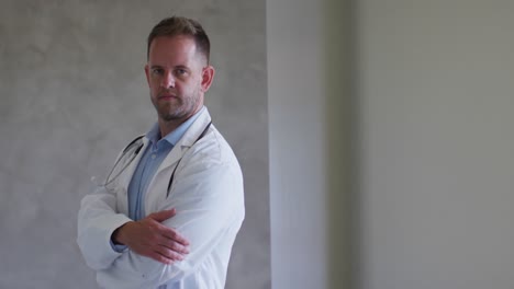 portrait of caucasian male doctor with arms crossed at home