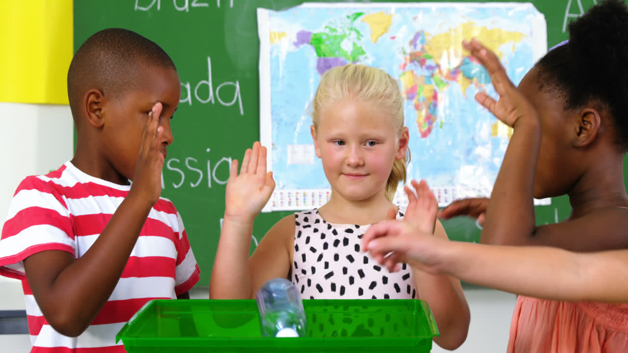 Schulkinder legen Abfallflasche in eine Recycling-Box im Klassenzimmer