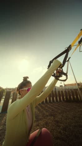 woman performing suspension training workout outdoors