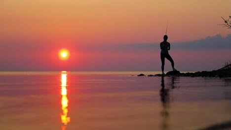 Woman-fishing-on-Fishing-rod-spinning-at-sunset-background.