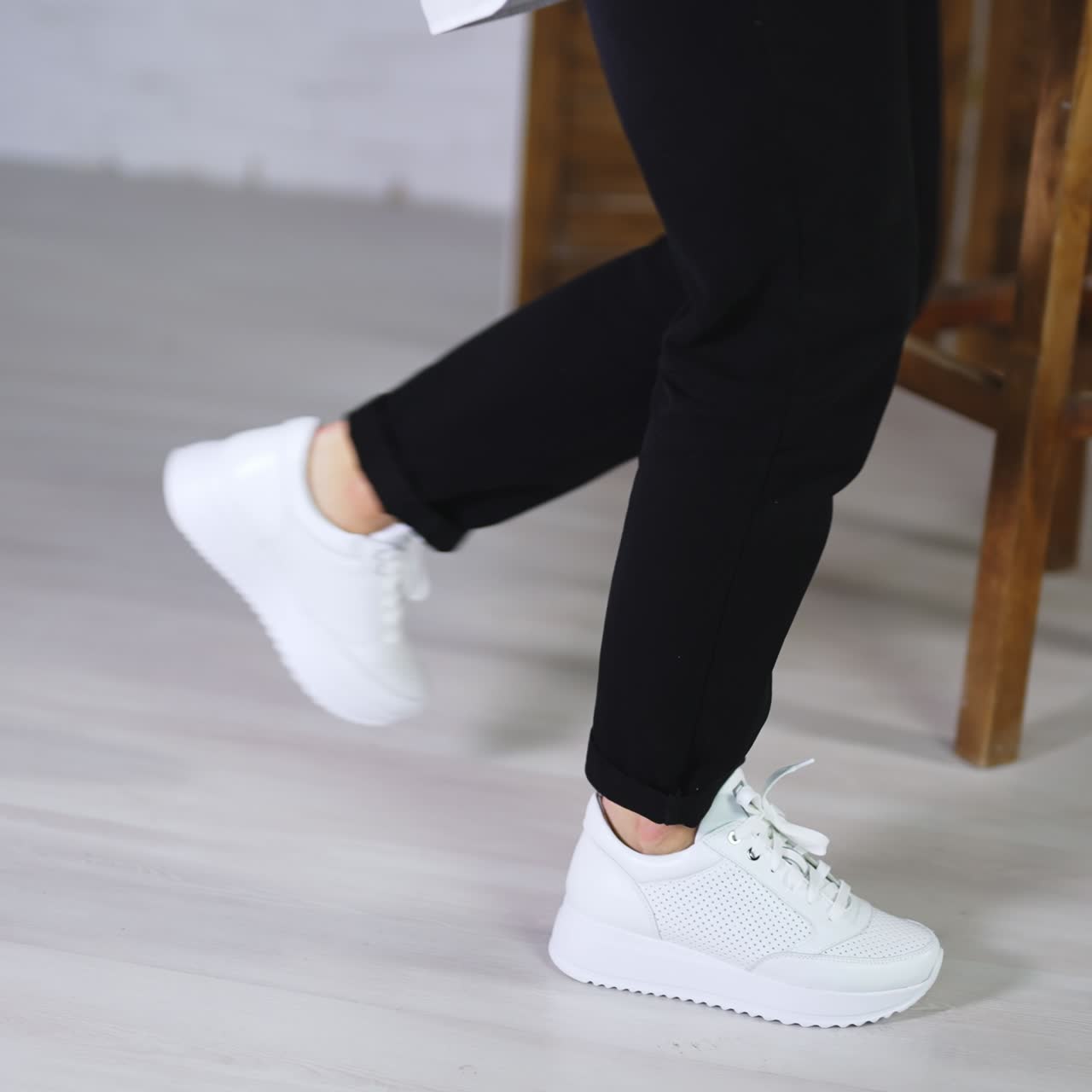 Fashionable white comfortable shoes presentation. Lady demonstrating beautiful footwear walking in the studio