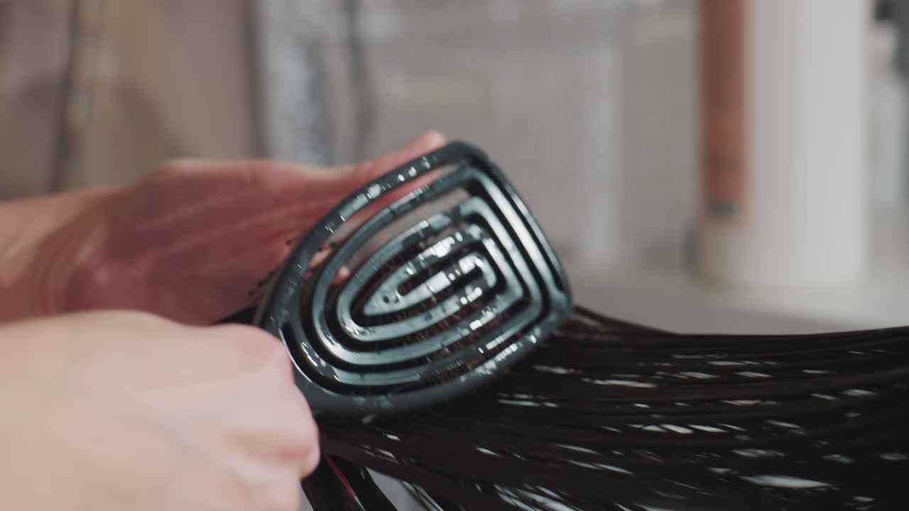 전문 헤어 스타일리스트가 머리카락을 엉키지 않게 하는 모습 클로즈업, 세면대 위에서 젖은 머리카락을 관리하는 스타일리스트에게 초점, 미용사가 세면대에서 젖은 머리카락을 부드럽게 펴고 엉킨 것을 푸는 모습 정밀 검사