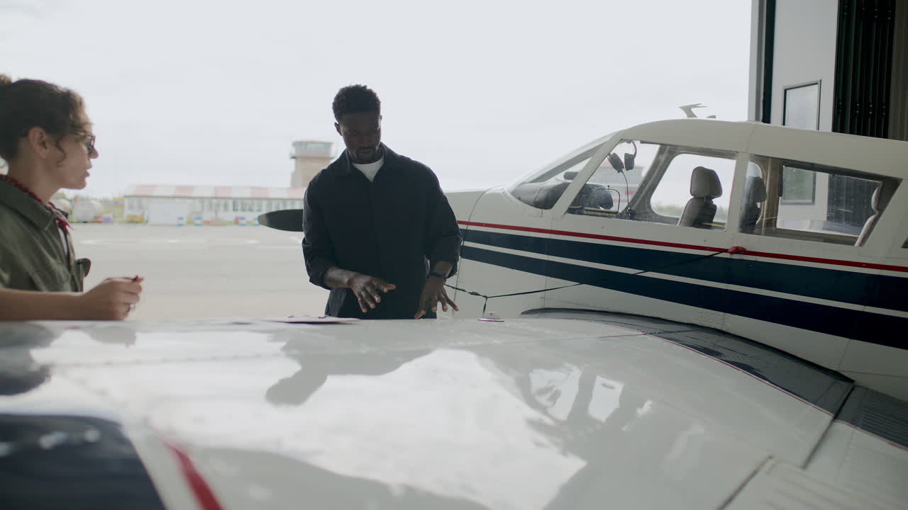 Aircraft Mechanic Explaining Details of Airplane Repair to Colleague