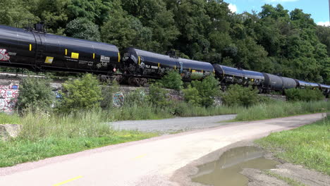 idle railroad cars on a siding alongside a bike path